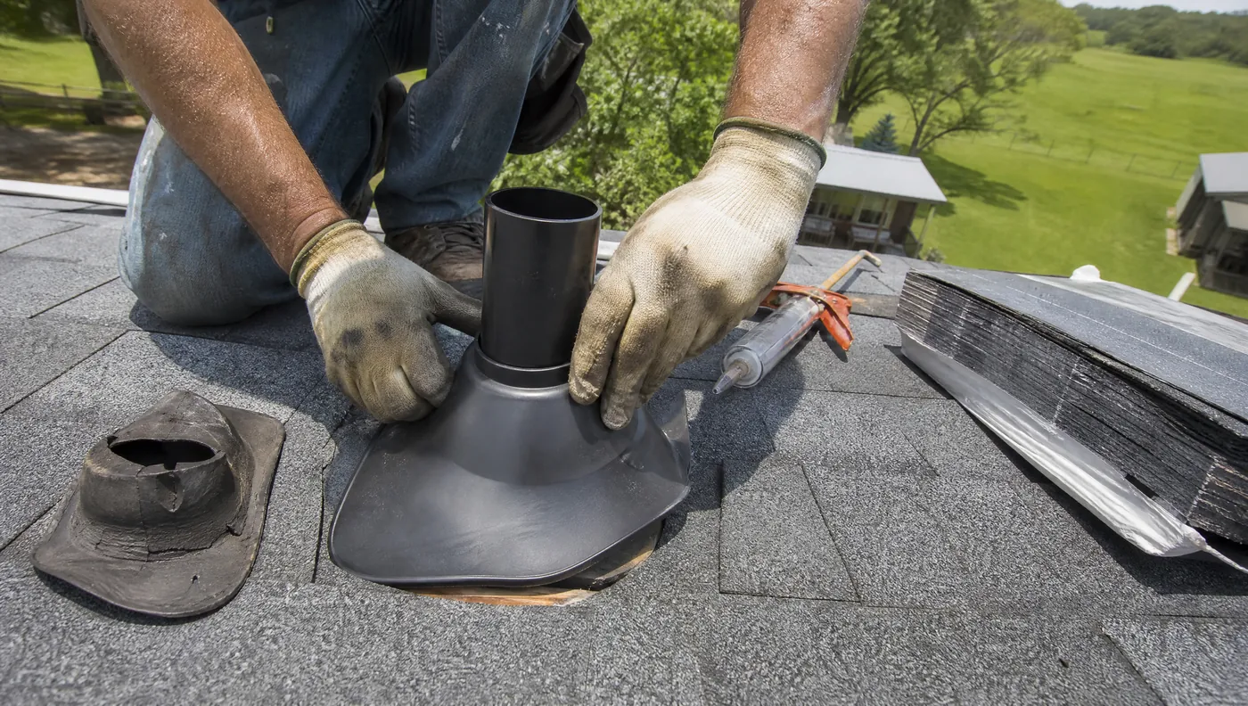 Roofer sealing a pipe boot flashing during a roof leak repair in Rosharon TX