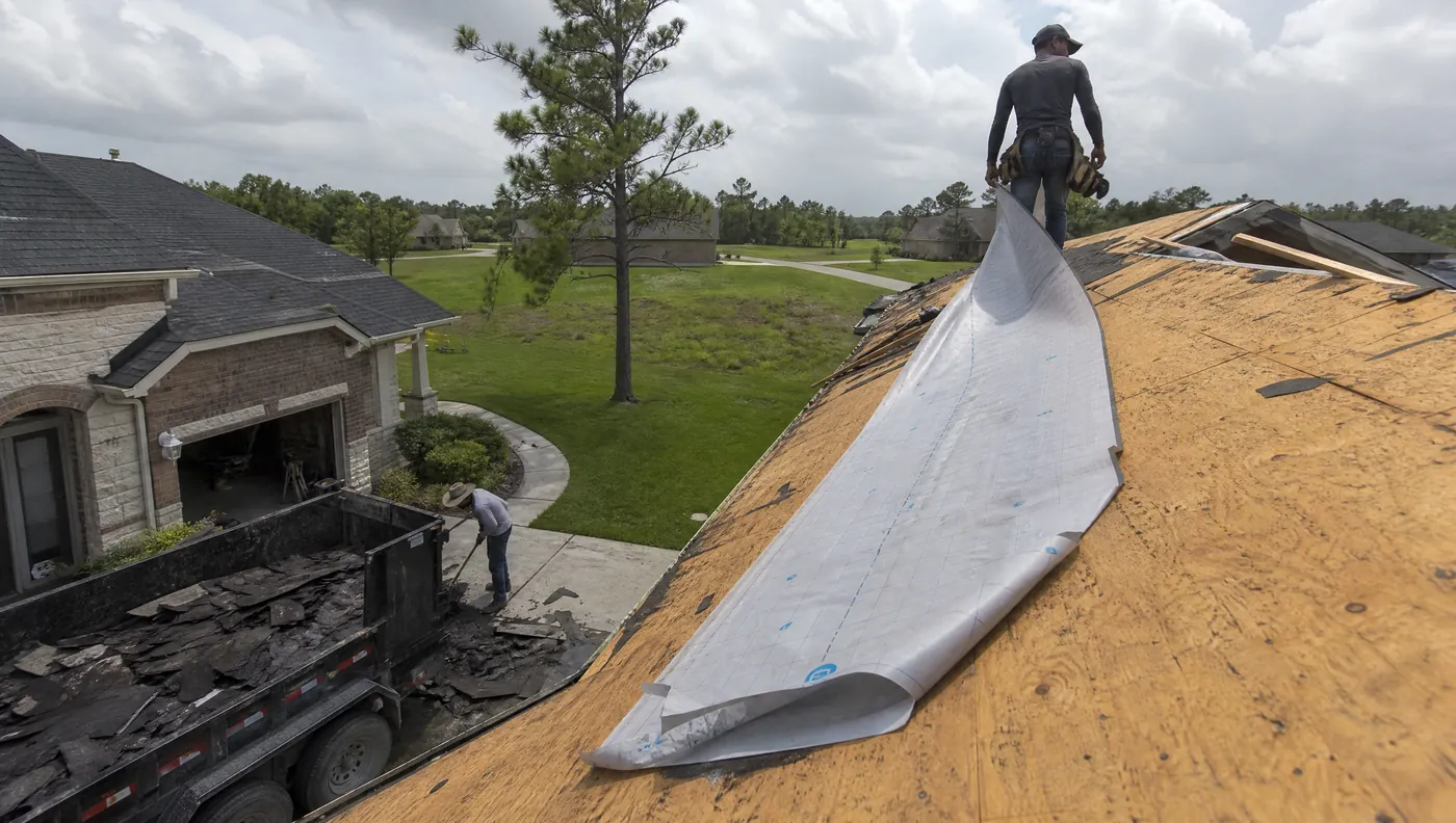 Tear-off crew stripping shingles from a Rosharon subdivision roof